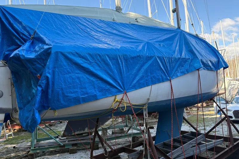 Slide: The Image of 1981 Catalina 22 sailboat covered with a blue tarp in a boatyard. - 19