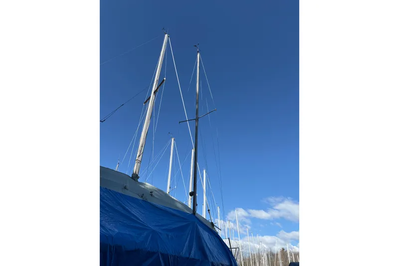 Slide: The Image of 1981 Catalina 22 sailboat with mast, covered in blue tarp, under clear blue sky. - 20