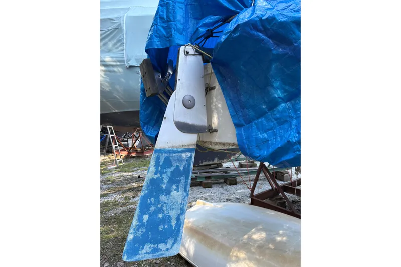 Slide: The Image of 1981 Catalina 22 sailboat rudder under blue tarp, stored on land. - 21