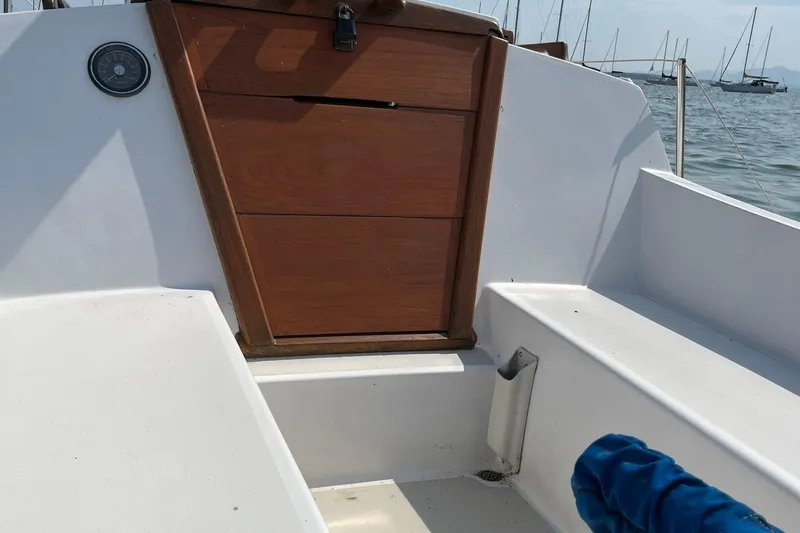 Slide: The Image of 1981 Catalina 22 sailboat cockpit with wooden hatch and white seating, docked in a marina. - 3