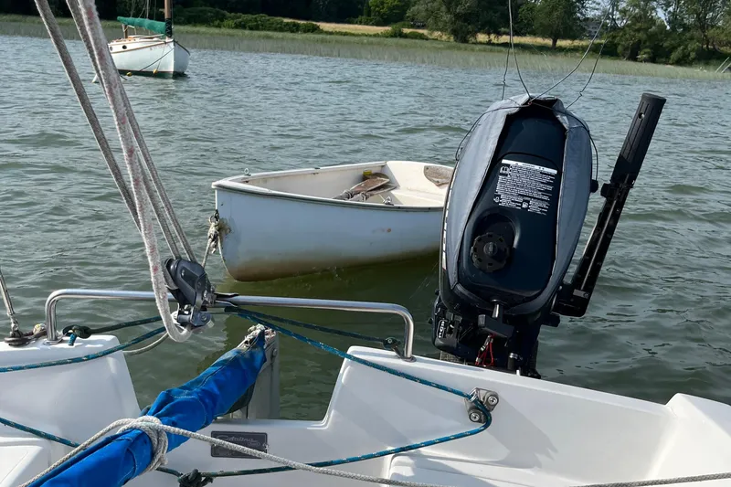 Slide: The Image of 1981 Catalina 22 sailboat with motor, docked on calm water, small boat nearby. - 7