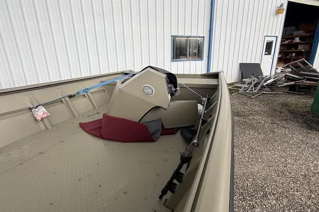 Slide: The Image of 2025 SeaArk 1860 MV boat interior, featuring steering console, parked near a metal building. - 2