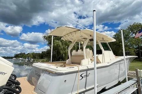 Slide: The Image of 2019 Scout 355 LXF boat docked under a partly cloudy sky. - 10