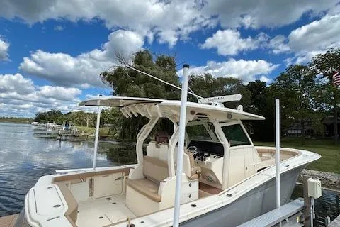 Slide: The Image of 2019 Scout 355 LXF boat docked by a scenic lake under a cloudy sky. - 11