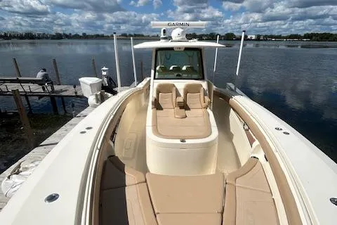 Slide: The Image of 2019 Scout 355 LXF boat docked by a serene lake under a cloudy sky. - 16