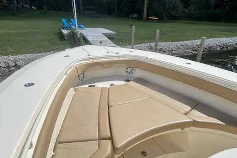 Slide: The Image of 2019 Scout 355 LXF boat with tan seating, docked near a grassy area. - 19