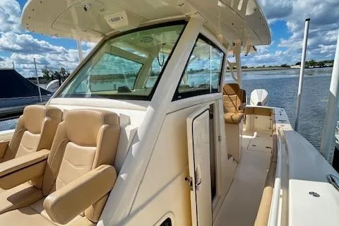 Slide: The Image of 2019 Scout 355 LXF boat with tan seating, docked by a calm waterway. - 21