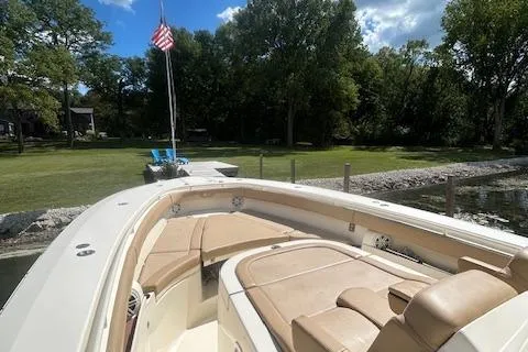 Slide: The Image of 2019 Scout 355 LXF boat with tan seating, docked near a grassy shoreline. - 22