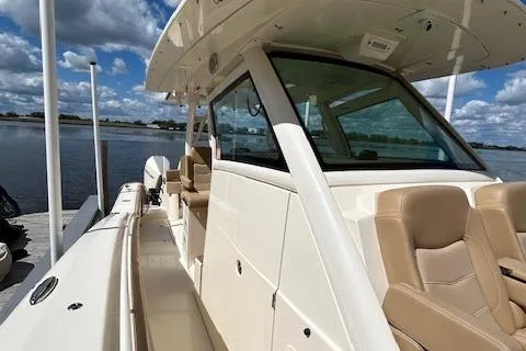 Slide: The Image of 2019 Scout 355 LXF boat docked by a serene waterfront under a cloudy sky. - 23
