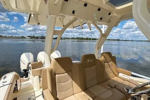 Slide: The Image of 2019 Scout 355 LXF boat interior with tan seating, lake view, and twin engines. - 26