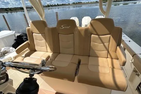 Slide: The Image of 2019 Scout 355 LXF boat with tan leather seating, steering wheel, and water view. - 27