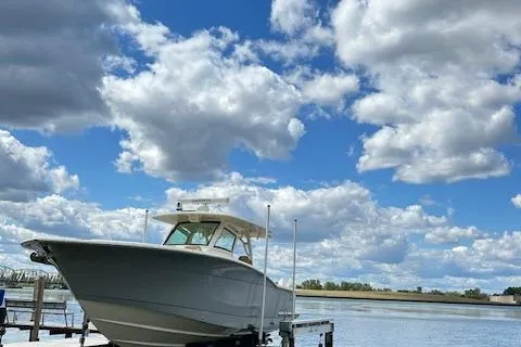 Slide: The Image of 2019 Scout 355 LXF boat docked under a cloudy blue sky. - 3