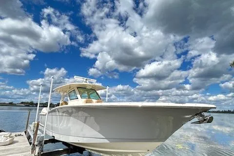 Slide: The Image of 2019 Scout 355 LXF boat docked under a vibrant cloudy sky. - 5