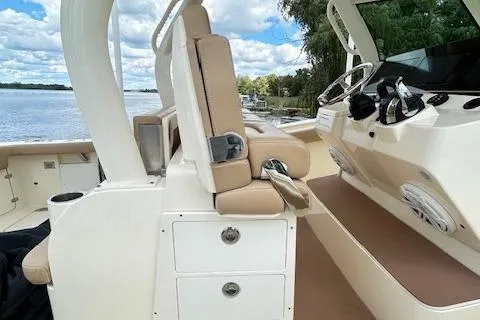 Slide: The Image of 2019 Scout 355 LXF boat interior with beige seating and control panel by the water. - 52