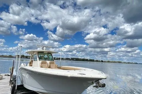 Slide: The Image of 2019 Scout 355 LXF boat docked on a serene lake under a cloudy sky. - 6