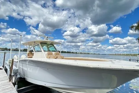 Slide: The Image of 2019 Scout 355 LXF boat docked under a vibrant, cloudy sky. - 7
