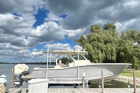 Slide: The Image of 2019 Scout 355 LXF boat docked by a scenic lake under a cloudy sky. - 9