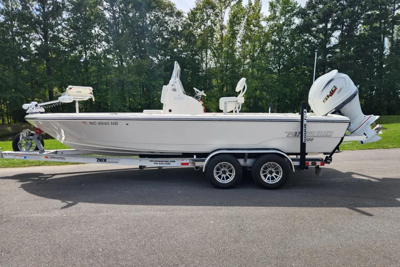 The Image of 2024 Pathfinder 2200 TRS boat on trailer, parked on road with forest background. - 0