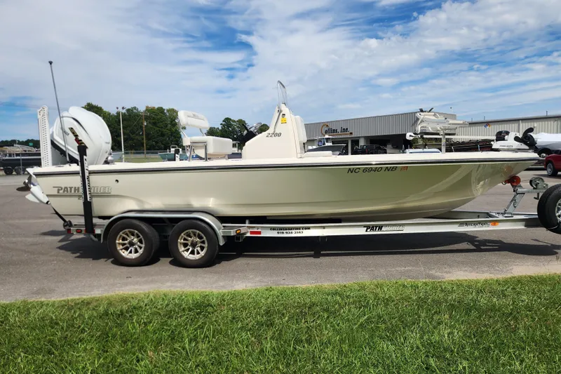 Slide: The Image of 2024 Pathfinder 2200 TRS boat on trailer, parked outdoors under a blue sky. - 6