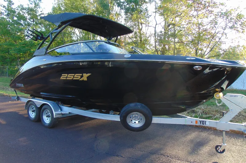 The Image of 2026 Yamaha Boats 255XD on trailer, sleek black design, parked outdoors. - 1
