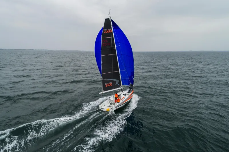 Slide: The Image of 2026 Jeanneau Sun Fast 3300 sailing on open sea with vibrant blue and black sails. - 4