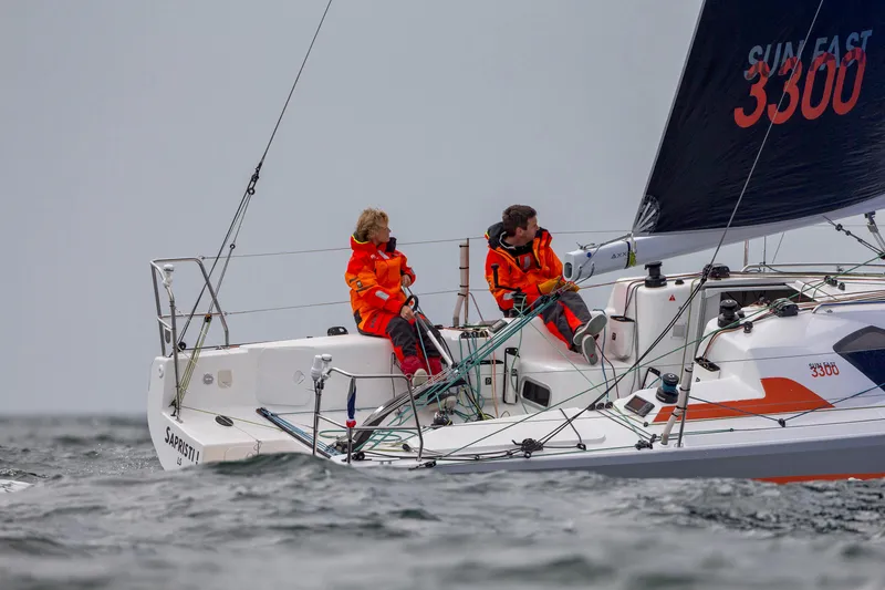Slide: The Image of 2026 Jeanneau Sun Fast 3300 sailing with crew in orange jackets on open water. - 6