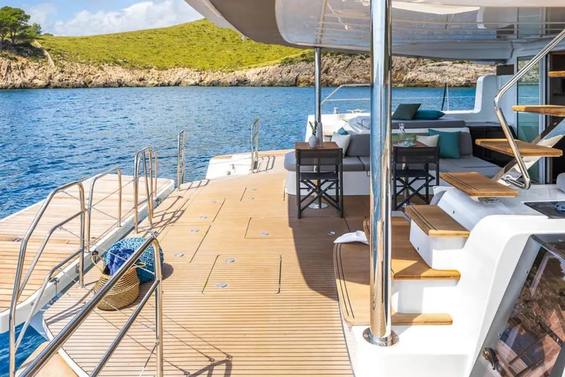 Slide: The Image of Luxurious Lagoon 60 yacht deck with seating, overlooking serene blue waters and lush green landscape. - 18