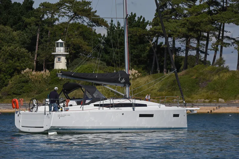 Slide: The Image of 2026 Jeanneau Sun Odyssey 380 sailboat on water near a lighthouse and trees. - 3