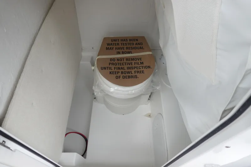 Slide: The Image of 2026 Sea Hunt Ultra 245 SE boat toilet with protective film and inspection notice. - 29