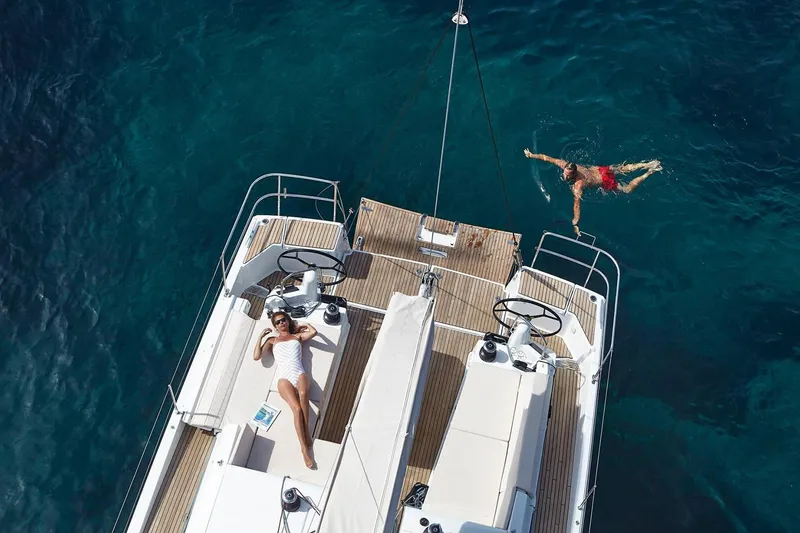 Slide: The Image of 2026 Jeanneau Sun Odyssey 490 yacht with people relaxing and swimming in clear blue water. - 14