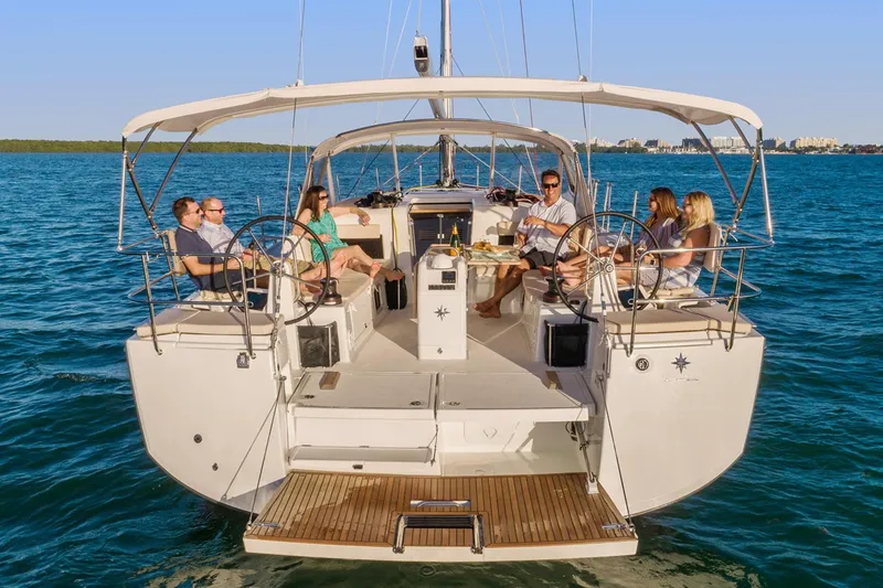 Slide: The Image of 2026 Jeanneau Sun Odyssey 490 yacht with people relaxing on deck, sailing on calm blue waters. - 17