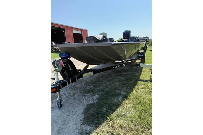 Slide: The Image of 2026 Lowe Stinger 175C boat on trailer, parked on grass near a red building. - 4