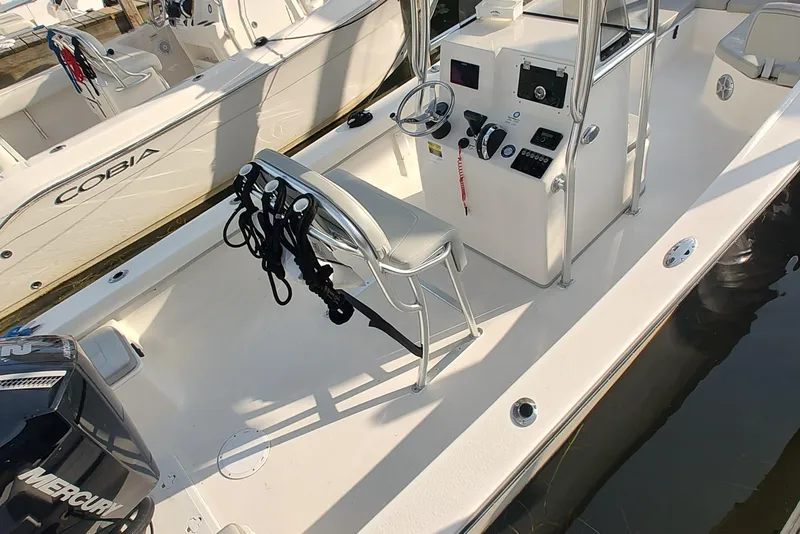 Slide: The Image of 2024 Mayfield 238CC boat interior with steering console and seating, docked beside another boat. - 6