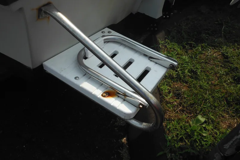 Slide: The Image of Rusty swim ladder on 1988 Boston Whaler 17 Super Sport boat, near grassy area. - 10