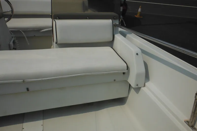 Slide: The Image of 1988 Boston Whaler 17 Super Sport interior seating with white cushions and steering wheel. - 21