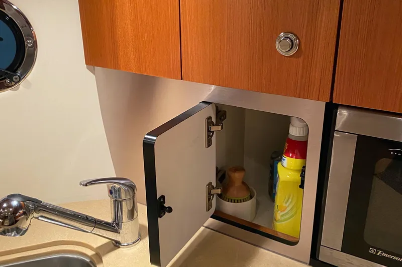 Slide: The Image of 2005 Tiara Yachts 3600 Sovran kitchen cabinet with open door, faucet, and cleaning supplies. - 31