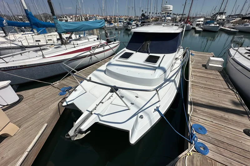 Slide: The Image of 2004 Glacier Bay 2680 Coastal Runner docked at marina, surrounded by sailboats. - 4