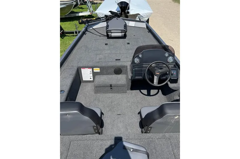 Slide: The Image of 2026 Lowe Legacy boat interior with steering console and seating, parked on grass. - 4