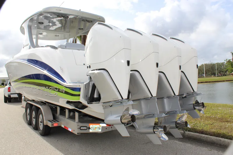 Slide: The Image of 2020 Mystic Powerboats M4200 with quad engines on a trailer by a lake. - 10