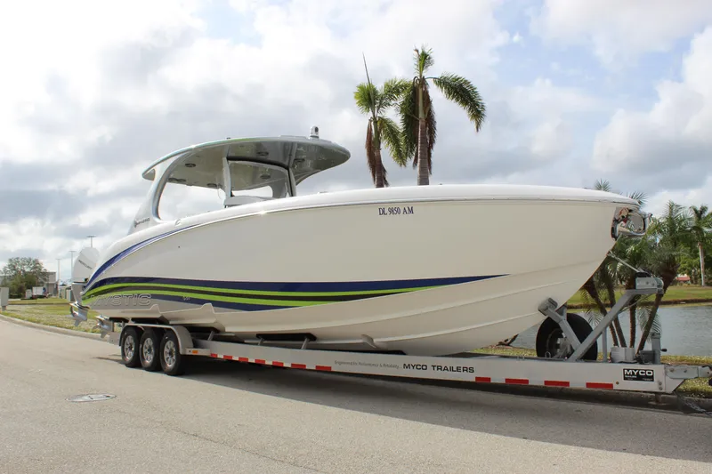 Slide: The Image of 2020 Mystic Powerboats M4200 on trailer, parked near palm trees and waterway. - 13