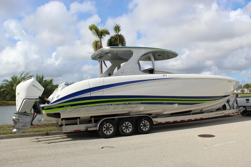 Slide: The Image of 2020 Mystic Powerboats M4200 on trailer, sleek design with vibrant accents, parked by palm trees. - 18