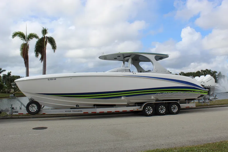Slide: The Image of 2020 Mystic Powerboats M4200 on trailer, sleek design with vibrant stripes, palm trees in background. - 2