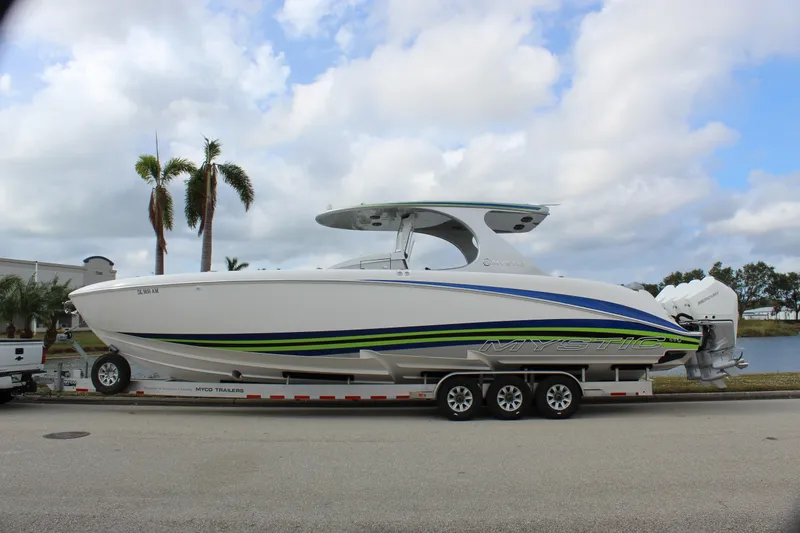 Slide: The Image of 2020 Mystic Powerboats M4200 on trailer, sleek design with vibrant accents, parked by palm trees. - 5