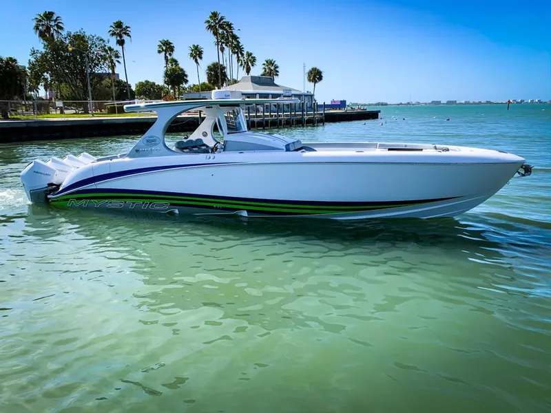 Slide: The Image of 2020 Mystic Powerboats M4200 cruising on clear waters near a tropical shoreline. - 58