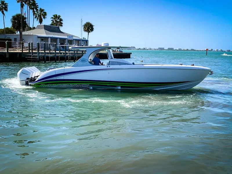 Slide: The Image of 2020 Mystic Powerboats M4200 cruising on clear blue water near a dock. - 63