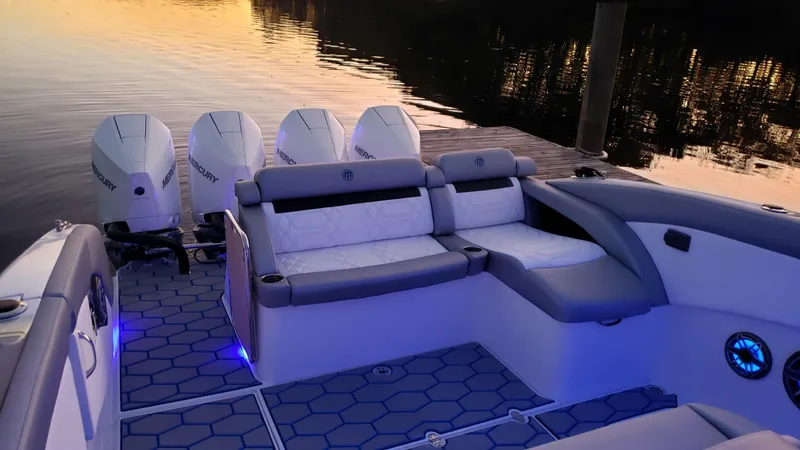 Slide: The Image of 2020 Mystic Powerboats M4200 with quad engines, luxurious seating, and ambient lighting at sunset. - 65