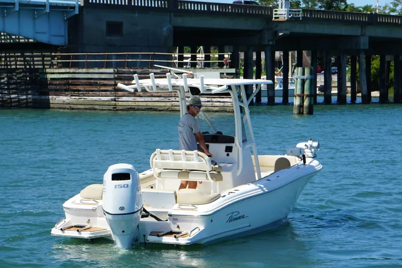 Slide: The Image of 2021 Pioneer 202 Islander boat cruising on a sunny day near a bridge. - 2
