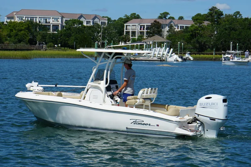 Slide: The Image of 2021 Pioneer 202 Islander boat cruising on a scenic waterway with buildings in the background. - 4