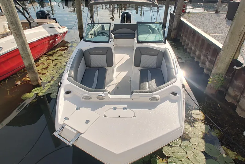 Slide: The Image of 2026 NauticStar 223 DC Deck boat docked, featuring spacious seating and sleek design. - 2