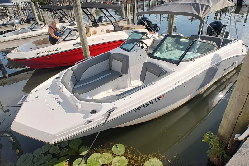 Slide: The Image of 2026 NauticStar 223 DC Deck boat docked, featuring sleek design and spacious seating. - 4